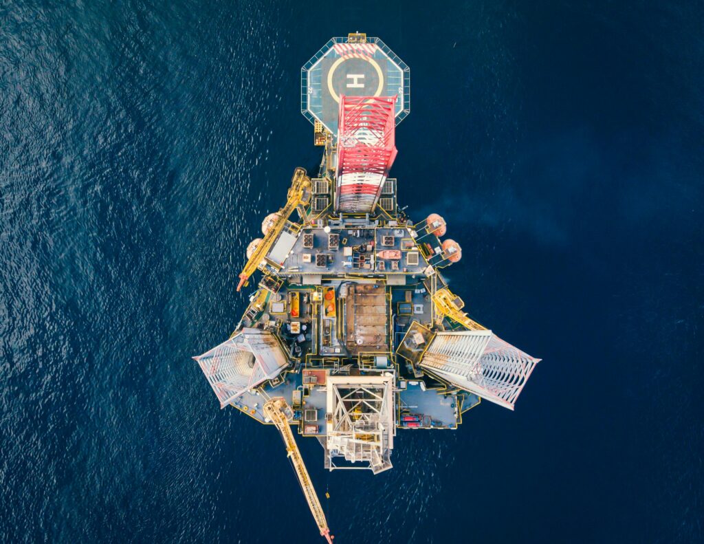 High-angle view of an offshore oil platform with helipad surrounded by deep blue ocean.