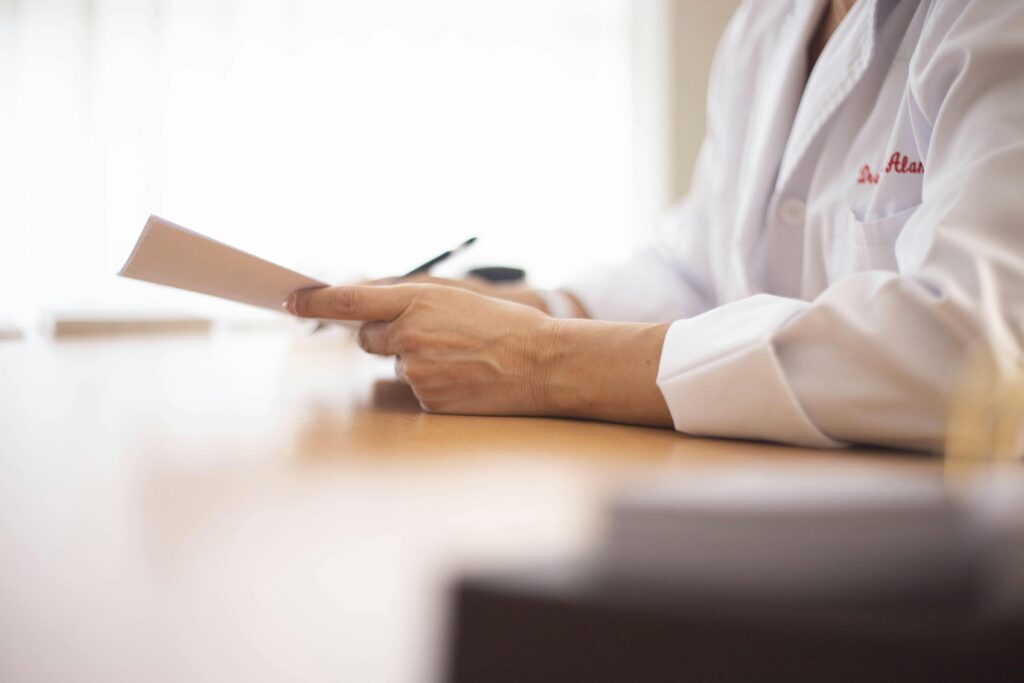 Close-up of a doctor in a lab coat reviewing paperwork at a desk.