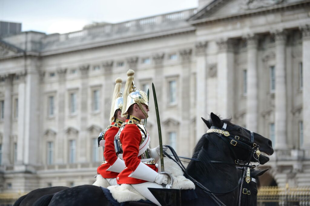 British Life Guards on horseback in ceremonial uniforms in front of Buckingham Palace, iconic London scene.