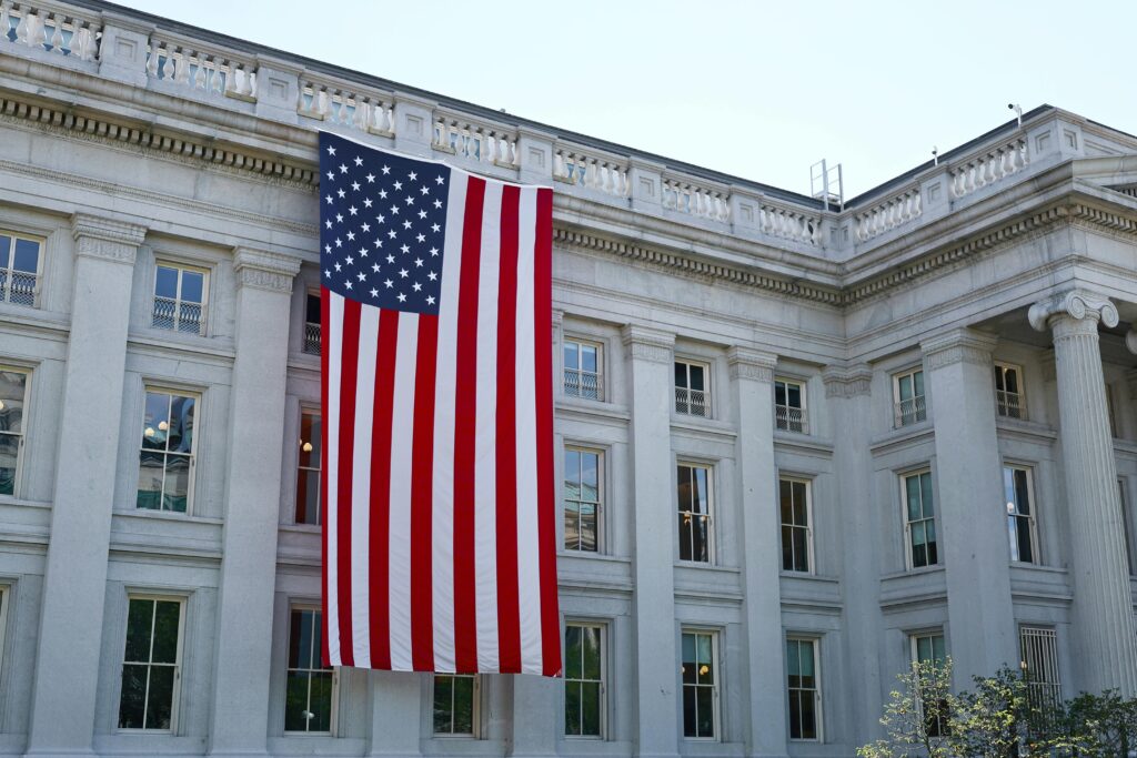 A large American flag hangs on a historic government building in Washington, D.C., showcasing national pride.