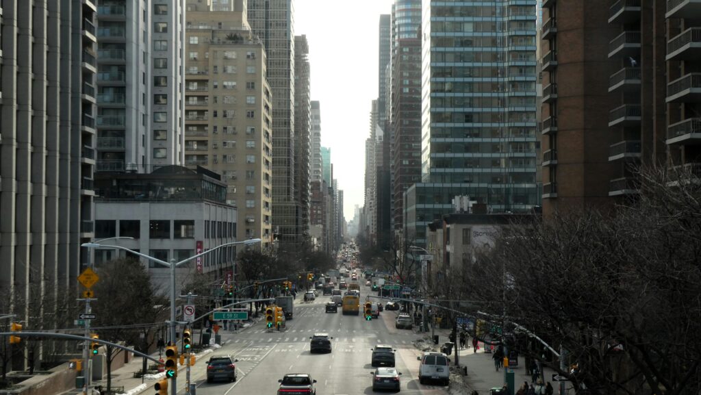 A bustling New York City street flanked by modern high-rise buildings, showcasing urban life.