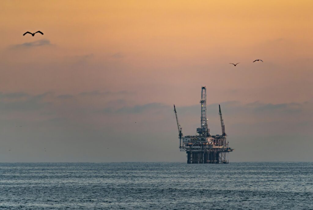 Oil platform silhouetted against a vibrant sunset in Huntington Beach, California.