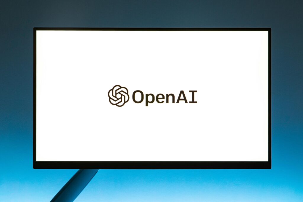 pexels-photo-15863000-15863000 Minimalistic display of OpenAI logo on a monitor with a gradient blue background, representing modern technology.