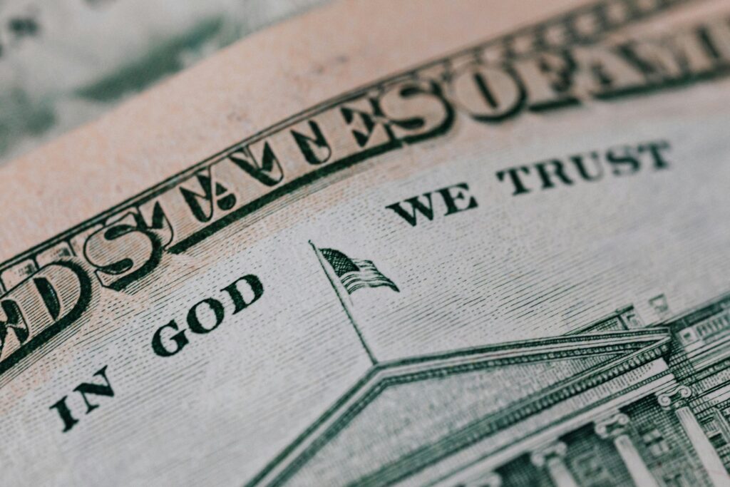 pexels-photo-4386156-4386156 Closeup of ten dollar with inscription In God We Trust bill placed on table with different money