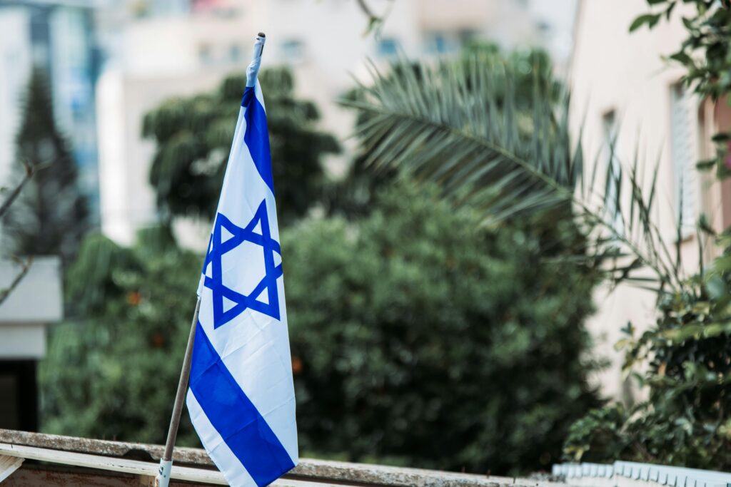 pexels-photo-5807072-5807072 Israeli flag displayed among urban greenery, reflecting national pride and identity.
